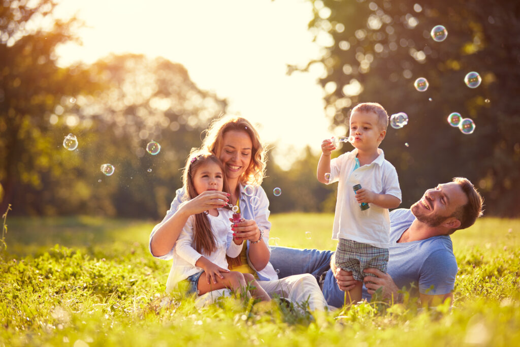 Family laying in a field together with kids blowing bubbles