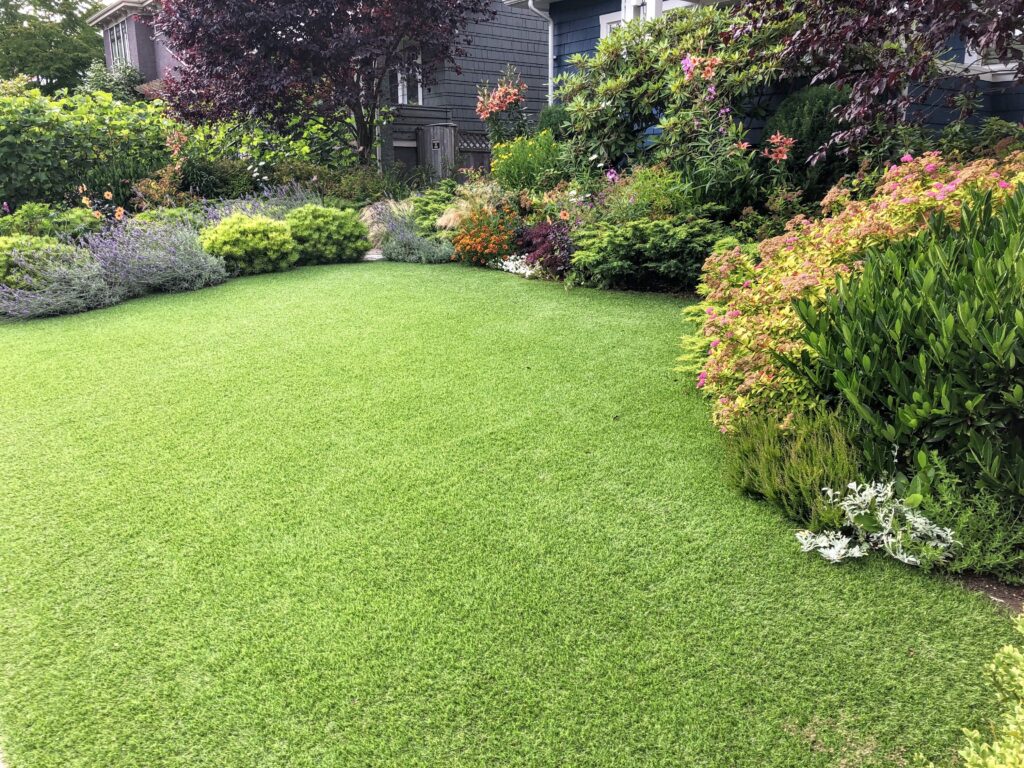 A beautiful artificial lawn in the front yard with nice flowers